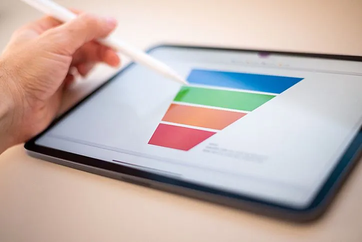 Sales marketing funnel showed on a tablet screen by a young marketer, sales manager pointing data with his pen.